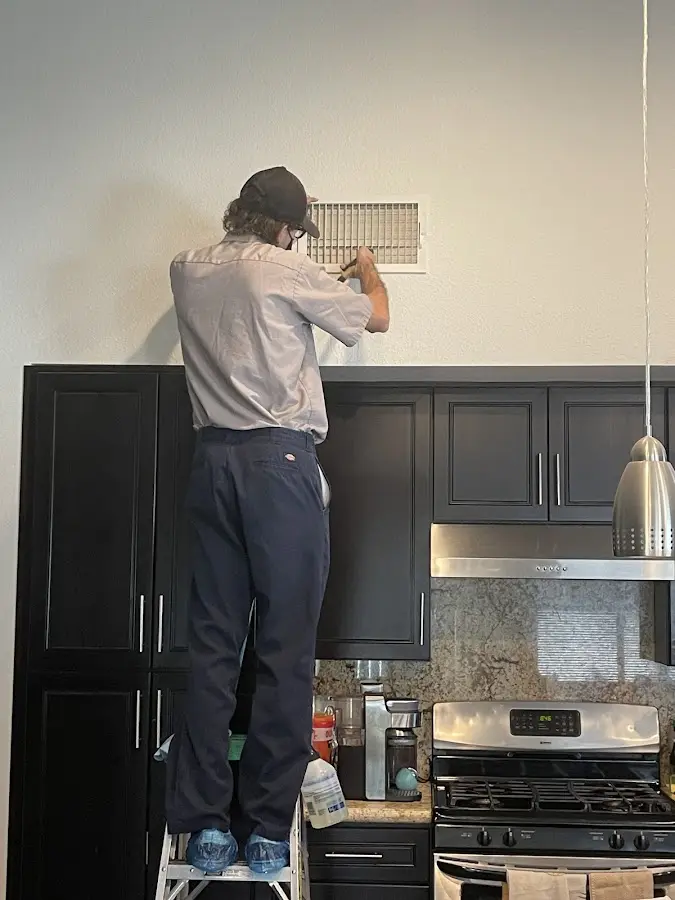 Technician inspecting an air vent during HVAC service in Conway